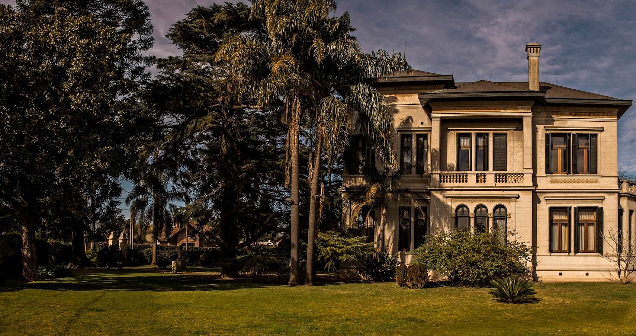Fachada principal señorial de Villa Grampa en Temperley de día rodeada de jardines centenarios y fuentes ornamentales
